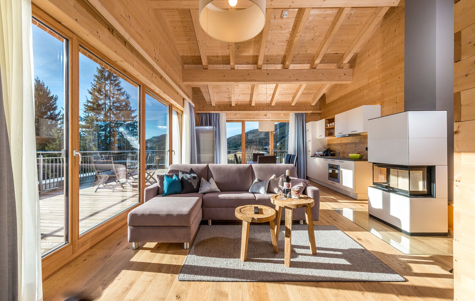 Lichtdurchfluteter Wohnraum aus Holz mit Küche und Kamin